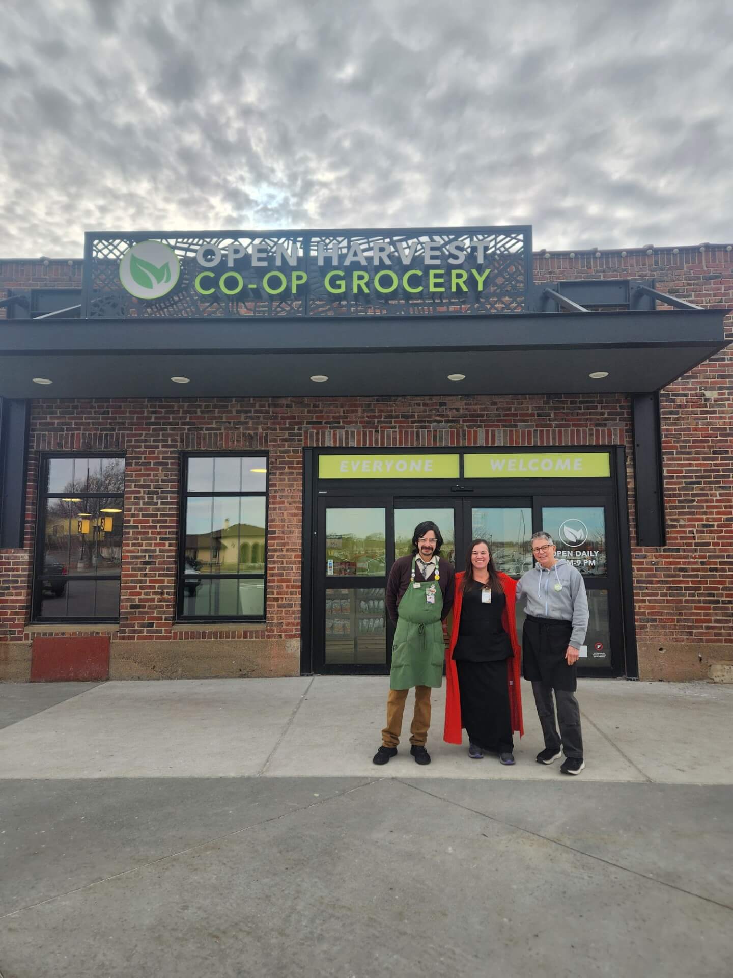 Three people standing in front of Open Harvest Co-Op Grocery building