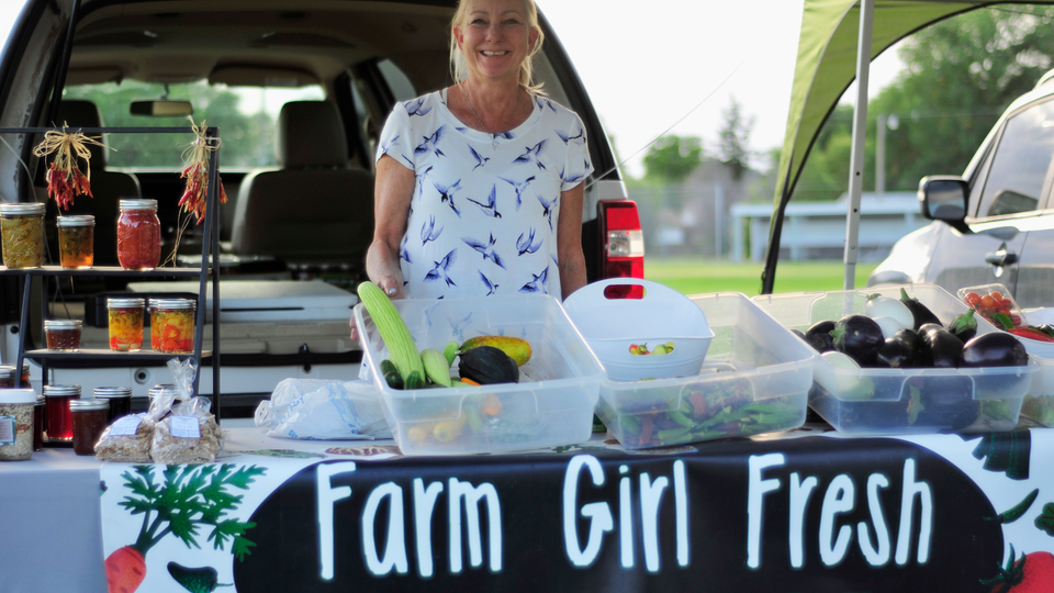 Vendor selling vegetables and jellies at farmers market